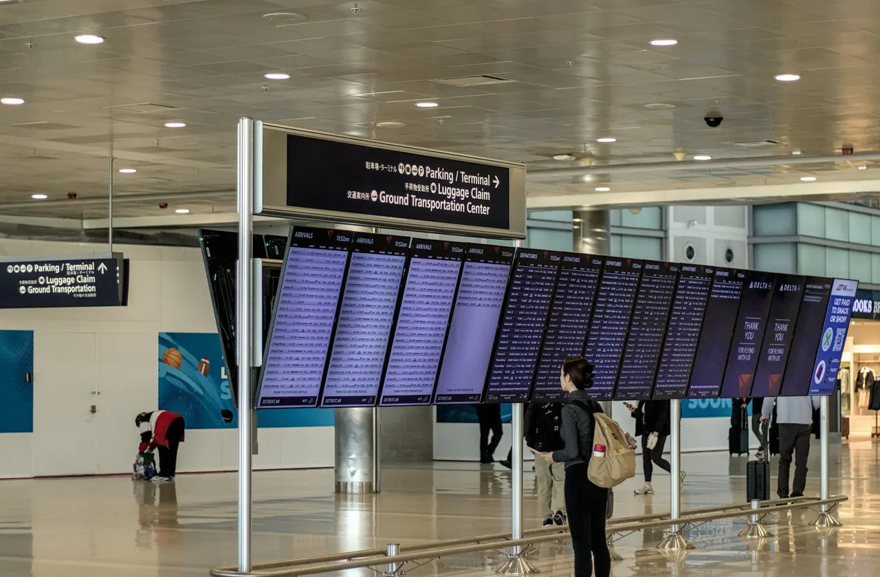 مسافر يحمل حقيبة ظهر، يظهر من الخلف وهو يقرأ لوحة الرحلات في المطار