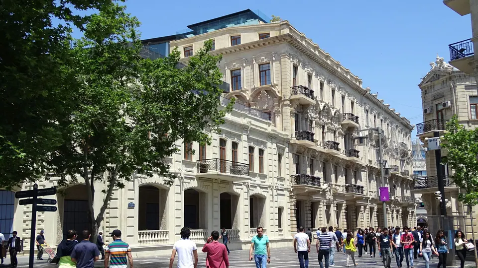 مشاة في شارع مرصوف بنقوش وسط باكو تصطفّ على جانبيه مبانٍ حجرية تاريخية مزخرفة