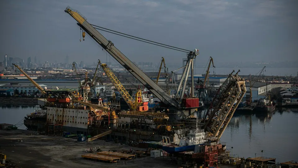 Large cranes, a vessel under repair and quayside equipment at an industrial waterfront in Baku.