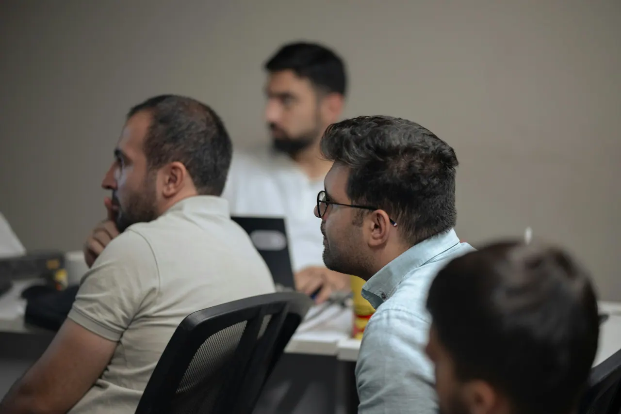 رجال يعملون على حواسيب محمولة حول طاولة خلال جلسة عمل